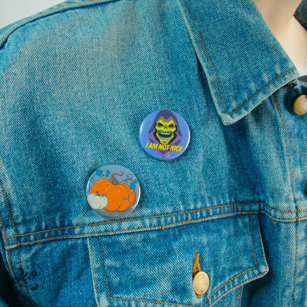 38mm button pin by Kilatora Design. Purple color with Skeletor and text "I am not nice". In the photo, two pins are attached to a denim jacket.