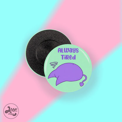 38mm magnet by Kilatora Design. Light green color with purple devil Tora character and text "always tired".