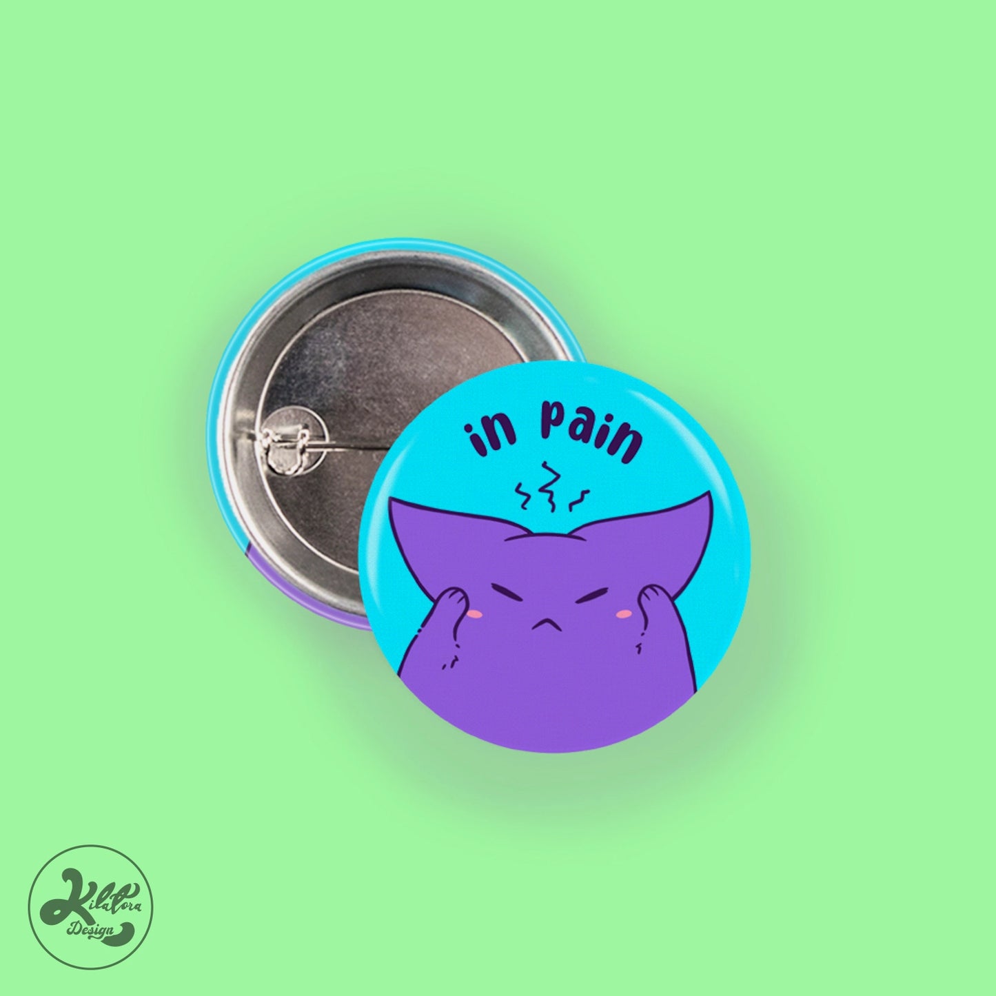 38mm button pin by Kilatora Design. Blue pin with Tora holding his head and the text "in pain".