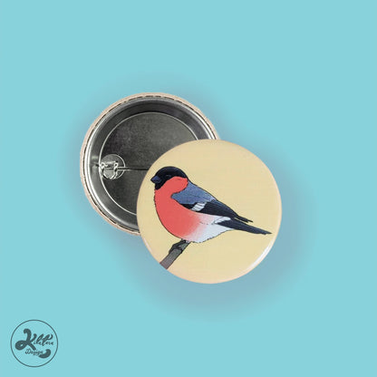 38mm button pin by Kilatora Design. Yellow color with bullfinch art.